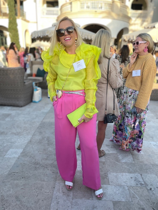 Taylor wears a neon ruffle blouse with bubblegum pink pants and a neon clutch with shell accessories
